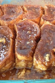 several pieces of french toast sitting in a glass baking dish with syrup on top and brown sugar on the bottom