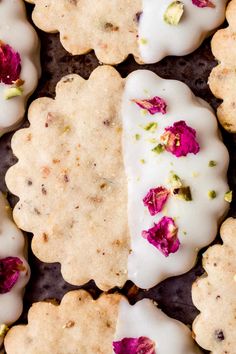 some cookies with white frosting and pink flowers on them are arranged next to each other