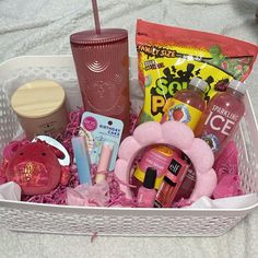 a white basket filled with lots of items on top of a bed next to a cup