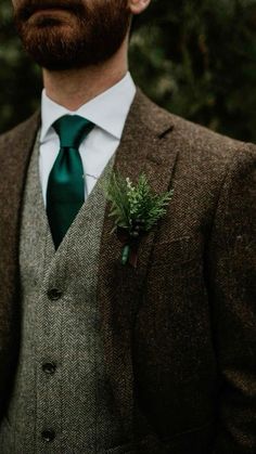 a man wearing a suit and tie with a green flower in his lapel pocket