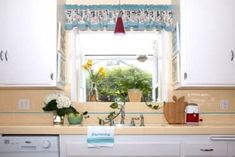 a kitchen with white cabinets and flowers in vases on the window sill above the sink