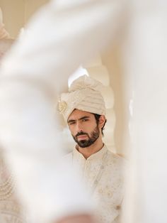 a man wearing a turban looking at his reflection in the mirror while he is getting ready to walk down the aisle