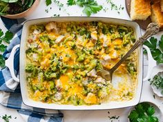 a casserole dish with chicken and broccoli in it next to bread