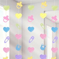 a baby mobile hanging from the ceiling in a child's room with hearts and pacifiers on it