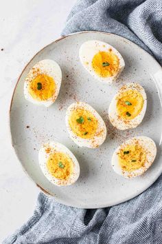 deviled eggs on a white plate with seasoning sprinkled around the edges