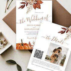 two wedding cards on top of a table next to some flowers and greenery,