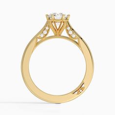 a yellow gold engagement ring with an oval center stone surrounded by small round diamonds, on a white background