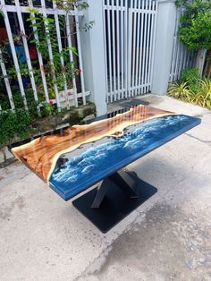 a wooden table sitting on top of a cement ground next to a white picket fence