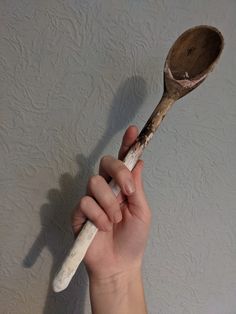 a person holding a wooden spoon in their right hand and pointing it at the wall