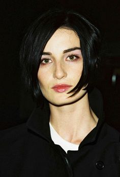 a woman with short black hair wearing a jacket