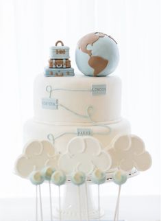 a three tiered cake with an earth globe on top and baby's toys