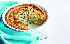 a quiche with cheese and broccoli in a white pie dish on a blue napkin