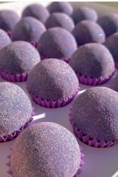 purple cupcakes sitting on top of a white plate covered in glittery frosting