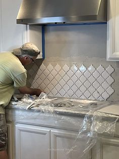 a man working on a kitchen backsplash