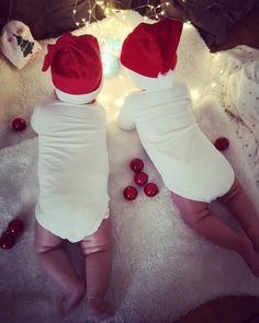 two babies are laying on the floor wearing christmas hats