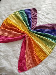 a multicolored knitted headband laying on top of a white furnishing