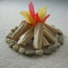 a fire pit made out of wood sticks and rocks on the floor with pebbles around it