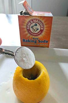 a person scooping sugar into an orange on a plate with a box of baking soda in the background