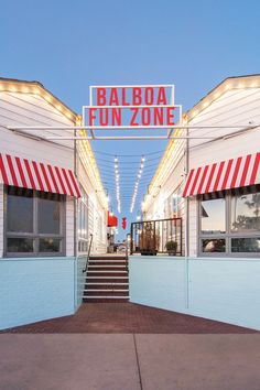 an entrance to a fun zone with lights on the roof and steps leading up to it