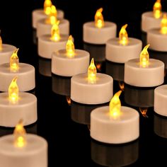 many lit candles are arranged in rows on a black surface with the words, 24 pack