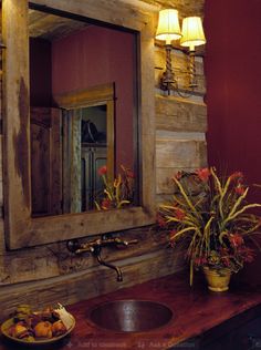 a bathroom sink sitting under a mirror next to a bowl of fruit on top of a wooden counter