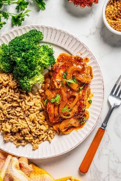 a white plate topped with pasta and broccoli next to other food on a table