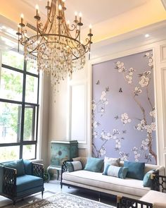 a living room filled with furniture and a chandelier hanging over the top of it