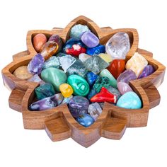 a wooden bowl filled with lots of different colored rocks and stones on top of each other