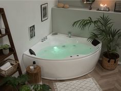 a large white bath tub sitting on top of a wooden floor next to a potted plant