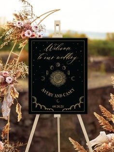 a black and gold wedding sign sitting on top of a wooden easel next to flowers