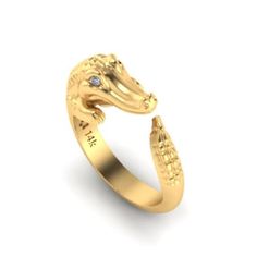 a gold ring with an alligator's head and diamond in the middle, on a white background