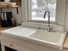 a white kitchen sink sitting under a window next to a counter with dishes on it