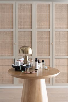 a wooden table topped with lots of bottles and other items next to a wall mounted cabinet