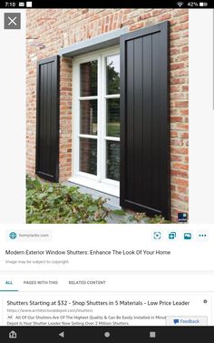 an image of a window with black shutters on the outside and brick wall behind it