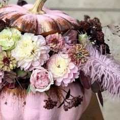 a pink pumpkin decorated with flowers and feathers