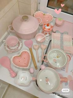 the table is full of pink and white dishes, utensils and other items