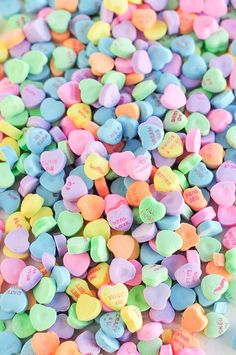 a pile of candy hearts sitting next to the words february written in black on top