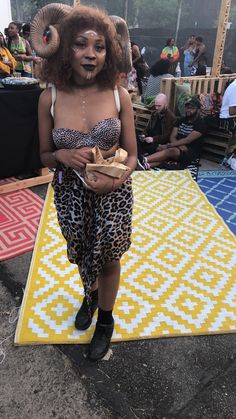 a woman in animal print clothing standing on a rug with an elephant's head painted on it