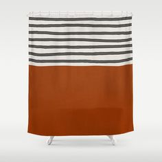 a striped shower curtain with an orange and black stripe on the bottom, in front of a white background