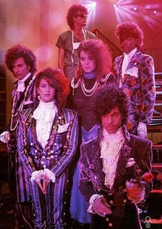 the group of people are posing for a photo in their fancy outfits and hair styles