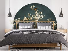 a bed with grey linens and white flowers in front of a green circular wall