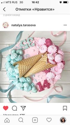 an ice cream cone is sitting on top of a pink and blue cake with flowers