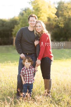 a man, woman and child posing for a photo in a field with tall grass