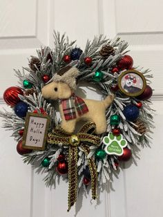 a christmas wreath with a stuffed animal hanging from it's side on a door