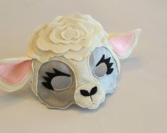 a sheep mask with a flower on it's head sitting on a white surface