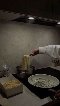 a chef is cooking pasta in a pan on the kitchen counter with other dishes nearby