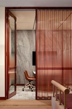 a room with a chair, desk and sliding glass doors that lead to the bedroom