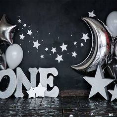 some balloons and stars are next to the word one in front of a black wall