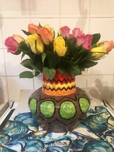 a vase filled with flowers sitting on top of a tiled counter next to a tile wall