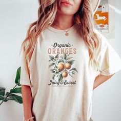 Elevate your style with this Organic Oranges Graphic T-Shirt featuring a vintage fruit design. Perfect for lovers of juicy and sweet Oranges, this tee carries a nostalgic look and celebrates Redlands, California. Ideal for casual outings, this shirt adds a unique touch to your wardrobe and showcases your love for fresh, organic produce. A great gift for fruit enthusiasts and those who appreciate retro designs. Available in various sizes and colors to suit your preferences. Product Features: Fabrication: Medium fabric (6.1 oz/yd² (206.8 g/m. Garment-dyed fabric. 100% ring-spun cotton Fit: Relaxed fit Sizing: Unisex Sizing Label: Sewn-in twill label Organic Short Sleeve T-shirt For Spring, Casual Orange Fruit Print Top, Organic Short Sleeve T-shirt With Screen Print, Vintage Fruit Print Top For Summer, Vintage Summer Top With Fruit Print, Organic White Crew Neck T-shirt, Vintage Orange Short Sleeve T-shirt, Vintage Fruit Print Crew Neck Tops, Vintage Crew Neck Tops With Fruit Print